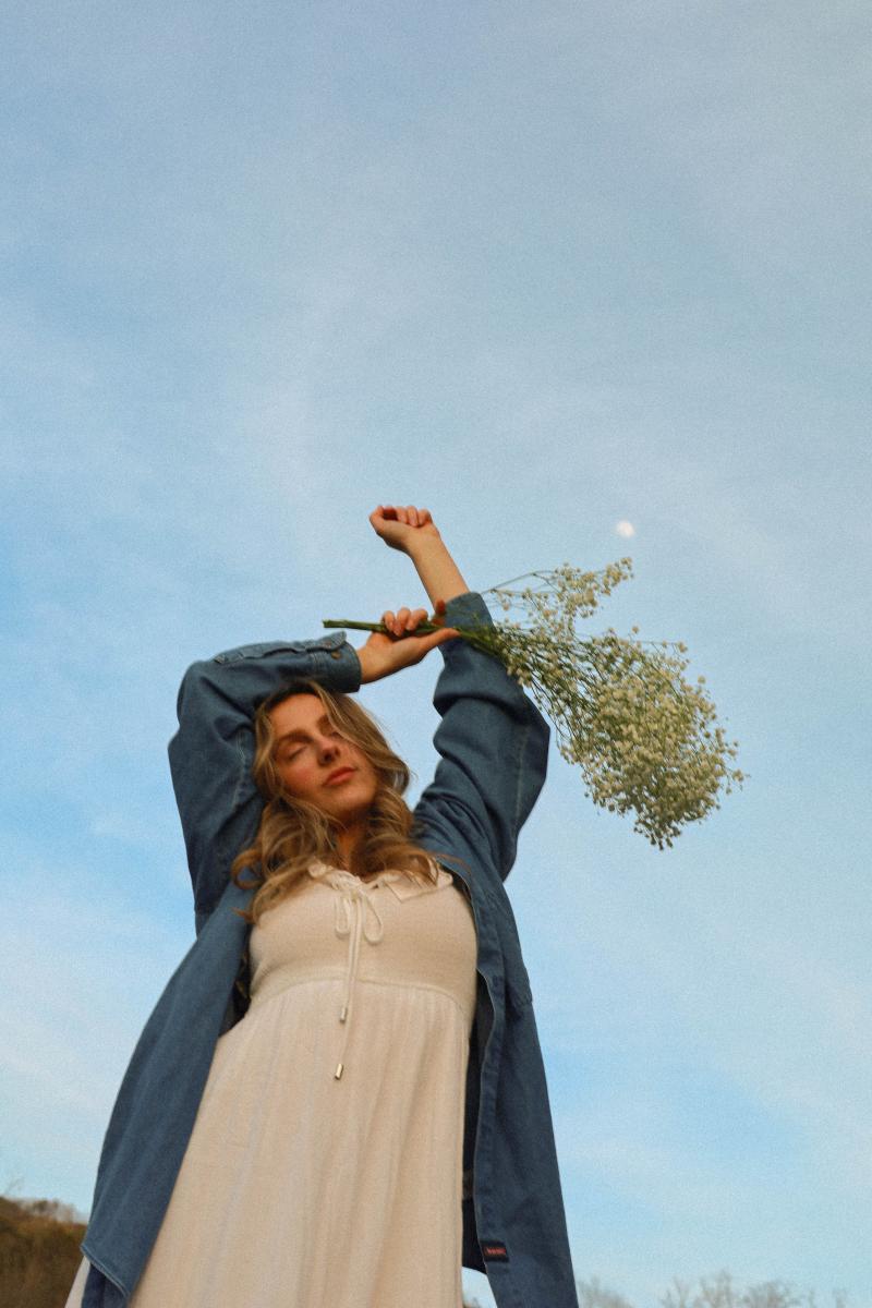 Young woman lifting a spray of baby's breath against an open blue sky