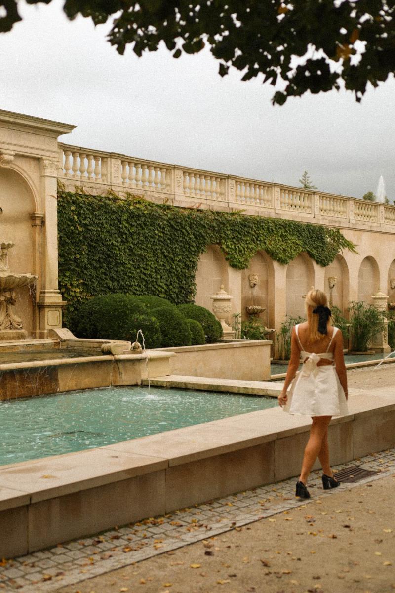 Portrait session beside a fountain terrace, ivy climbing the stone arcade behind