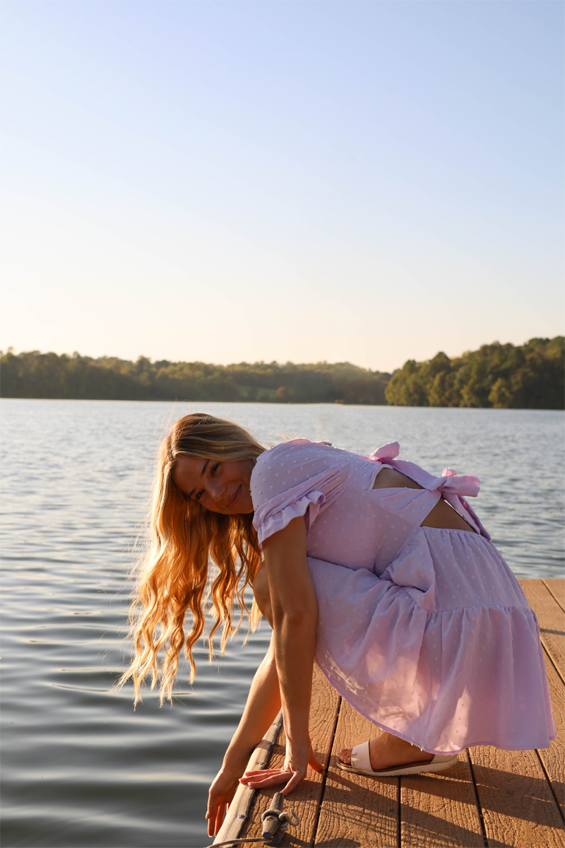 Senior portrait on a wooden dock at the water's edge, late sun across the lake
